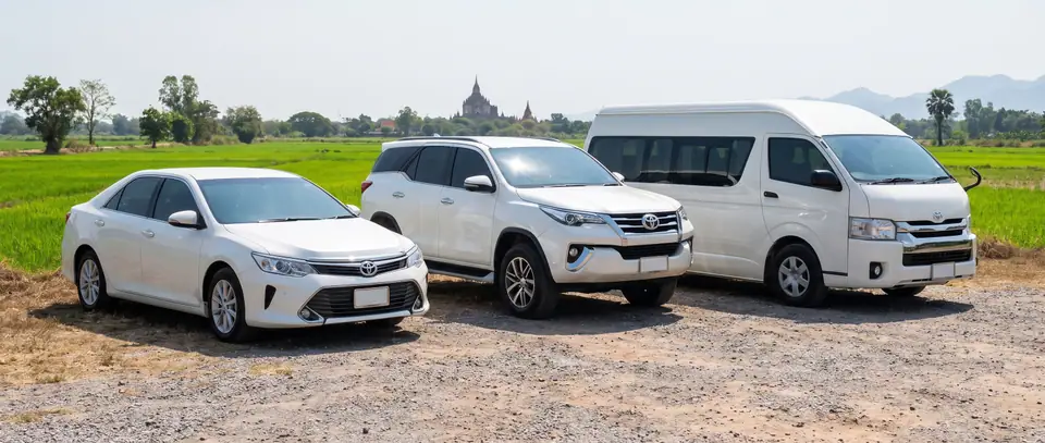 รถเก๋ง รถ SUV และรถตู้ จอดหน้าทุ่งนาและวัด